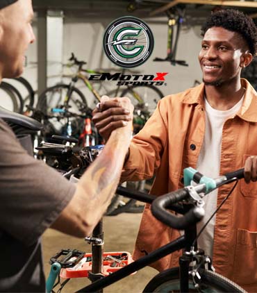 eMotoX Sports technician assisting a customer with bicycle service in workshop | eMotoX Sports