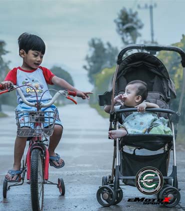 Child riding a bicycle alongside a baby in a stroller, representing trust, safety, and family values | eMotoX Sports