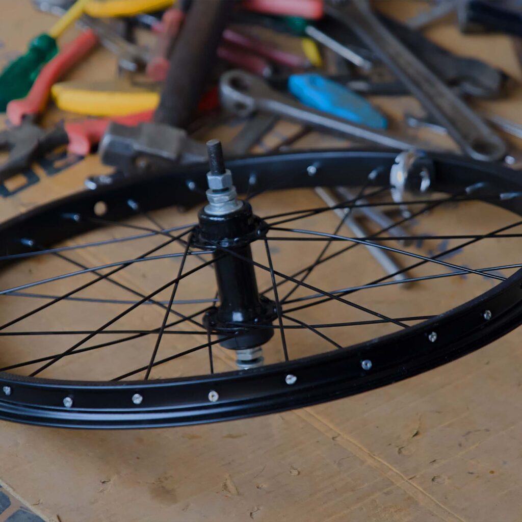 Bicycle wheel build and spoke tensioning in progress, showing a wheel hub, spokes, and rim during professional bike servicing at eMotoX Sports