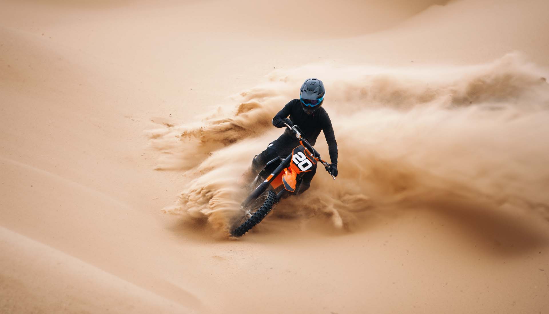 Motocross rider carving through desert sand on an off-road dirt bike | eMotoX Sports