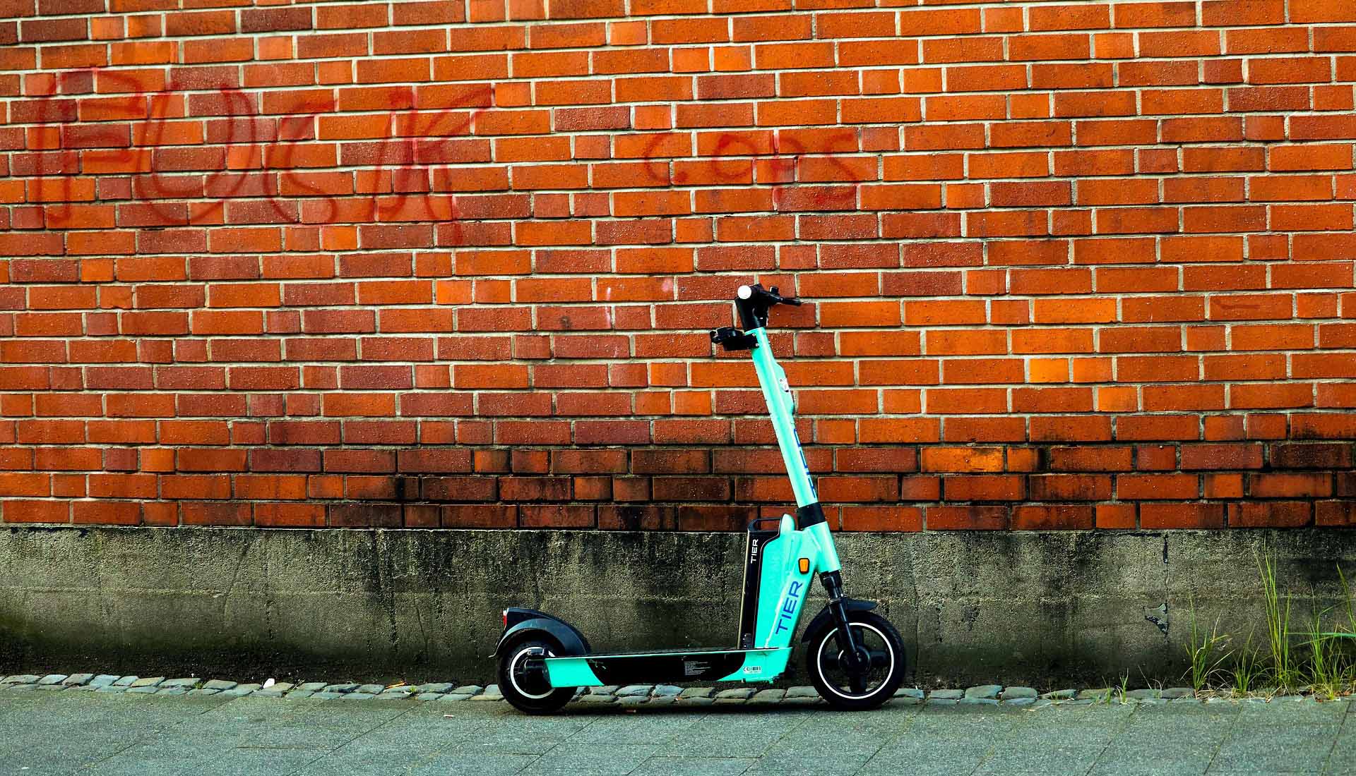 Electric scooter parked against a brick wall in an urban setting | eMotoX Sports