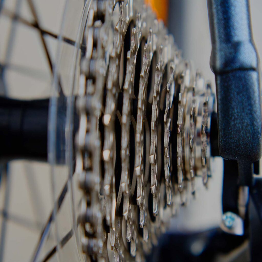Close-up of a bicycle rear cassette and drivetrain gear cluster, showing clean sprockets and chain alignment - eMotoX Sports