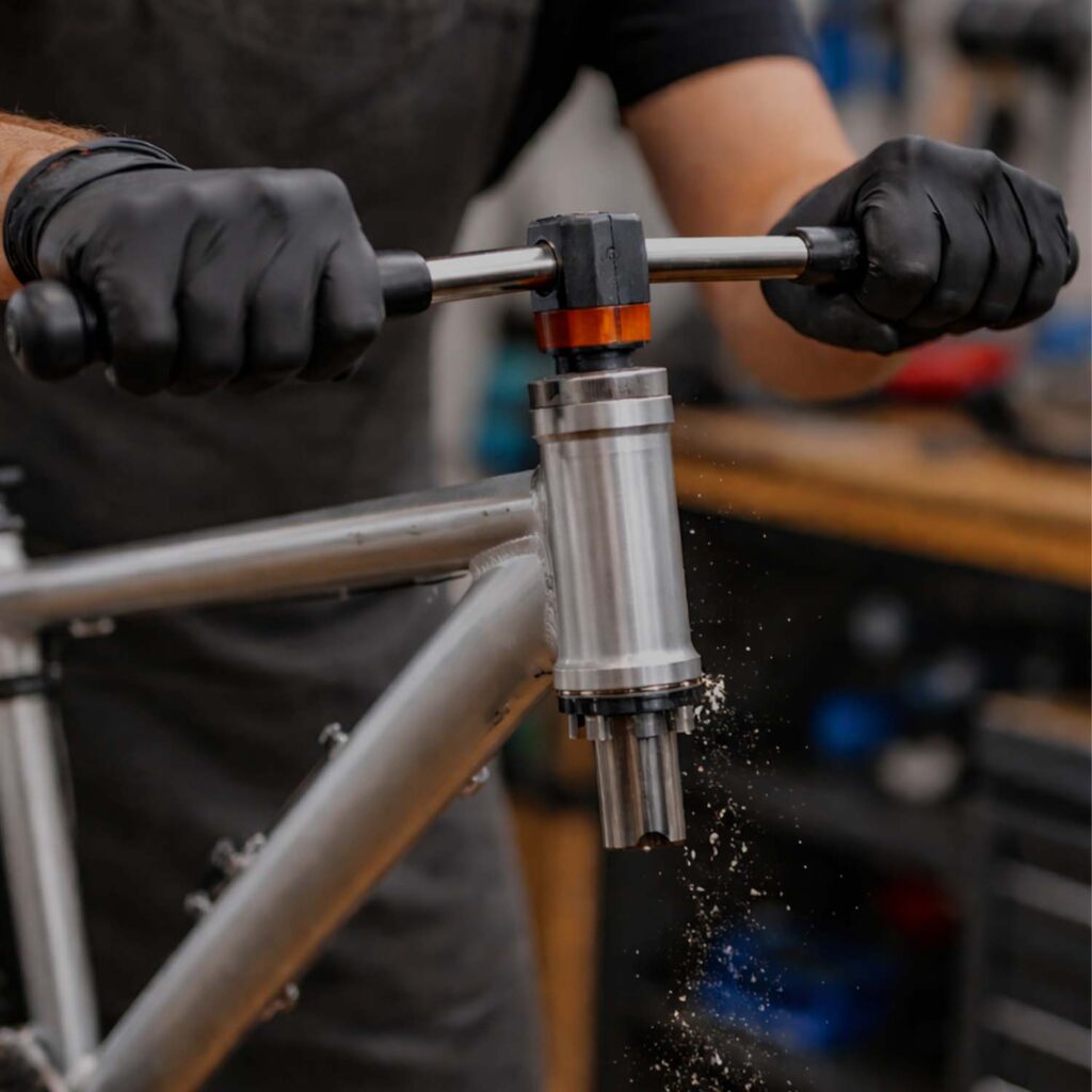 Bicycle mechanic reaming and facing a bike frame head tube using a precision workshop tool. | eMotoX Sports