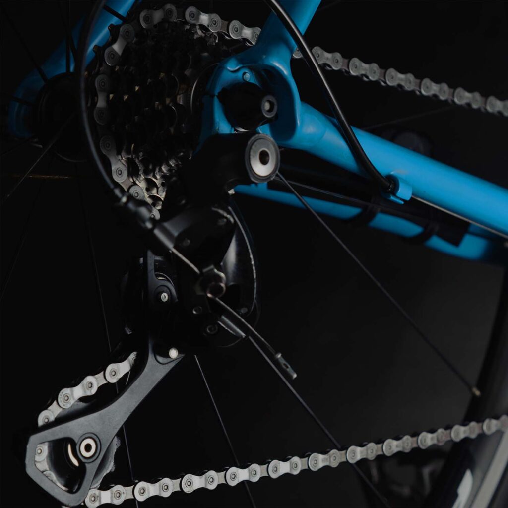 “Bicycle rear derailleur, chain, and cassette showing drivetrain components during professional servicing. | eMotoX Sports