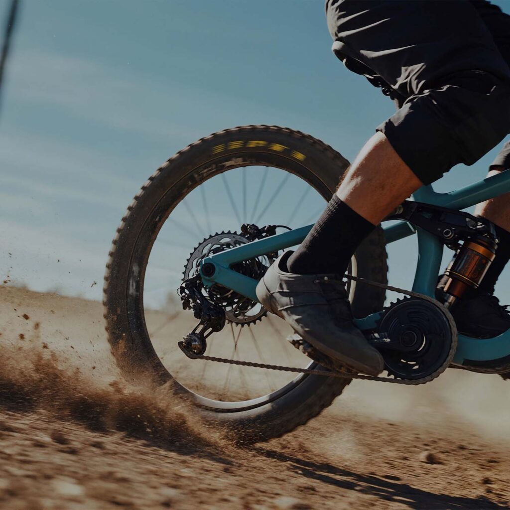 Rear wheel and drivetrain of an electric mountain bike kicking up dirt during off-road riding. | eMotoX Sports