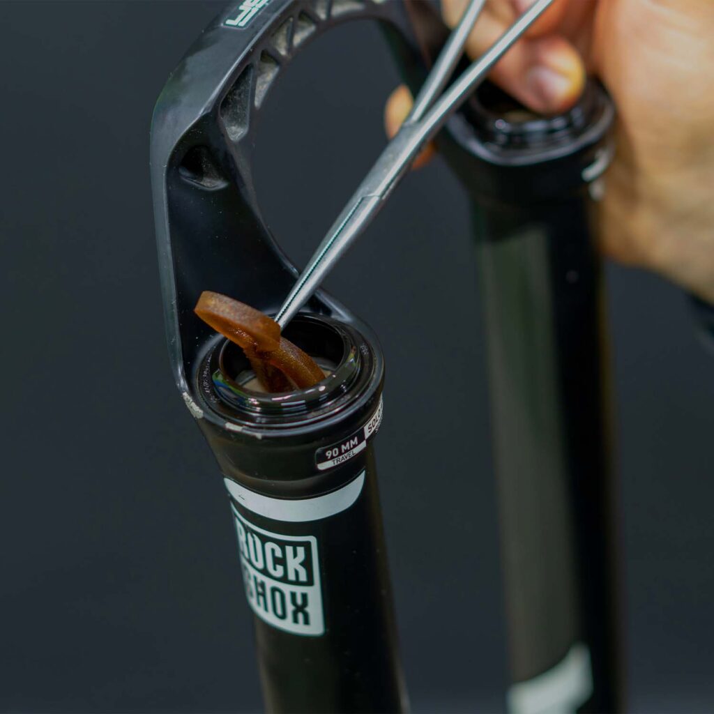 Mountain bike suspension fork being serviced with internal lubrication and inspection during professional suspension maintenance. | eMotoX Sports